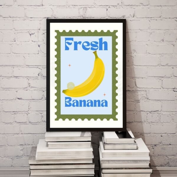 The Fresh Bananas artwork features a yellow banana with the phrase in blue, designed like a postage stamp. Its shown against a white brick wall, placed on books.