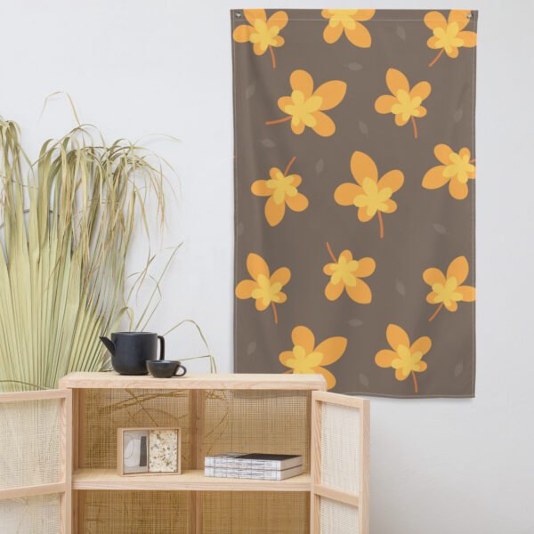 The Yellow leaf pattern tapestry wall hanging is displayed above a light wooden shelf with a black teapot, cup, and a tall green plant beside it.
