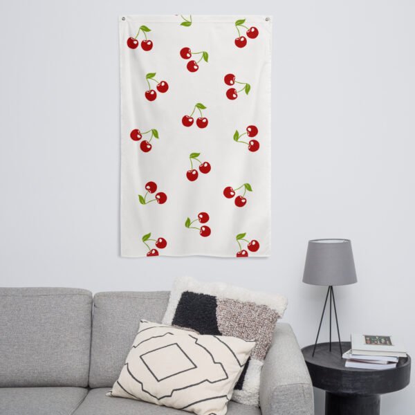 A Cherry pattern tapestry with red cherries and green leaves hangs above a gray sofa.