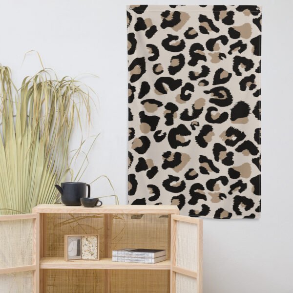 A Leopard print tapestry with black, brown, and tan leopard spots hangs above a light wood cabinet.
