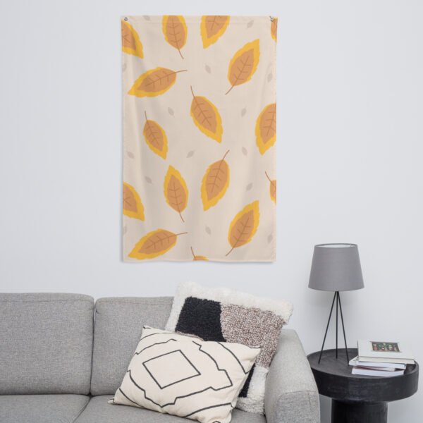 An Autumn leafs pattern tapestry in beige with orange and yellow leaves hangs above a gray sofa with two pillows.