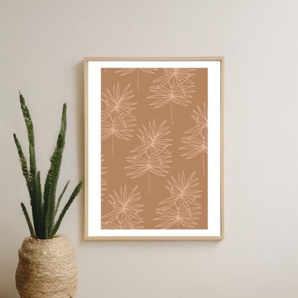 Framed artwork featuring a leaf pattern on a brown background, displayed on a wall.
