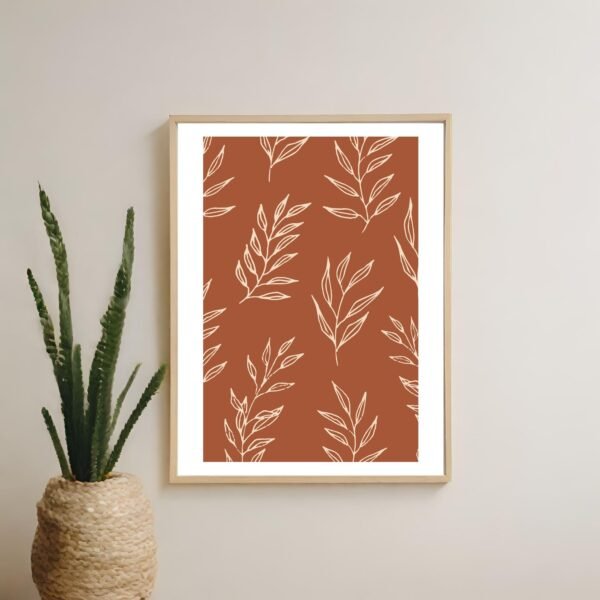 Framed artwork featuring a leaf pattern on a rust-colored background.