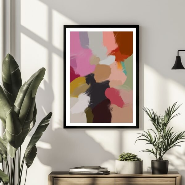 Framed abstract artwork featuring a blend of colors including pink, red, and green on a wall.