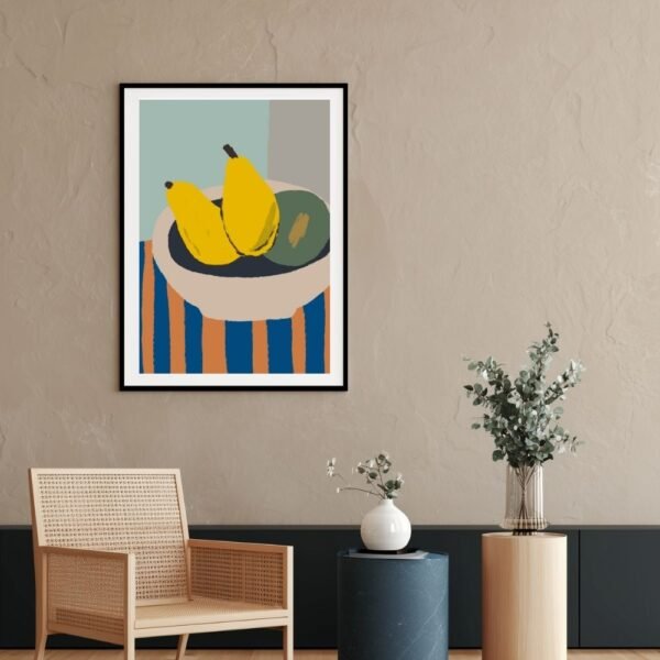 Framed artwork depicting two bananas and a green fruit in a bowl on a striped surface.
