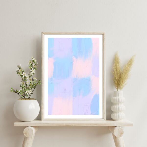 Framed abstract artwork featuring pastel blue and pink brush strokes displayed on a shelf.