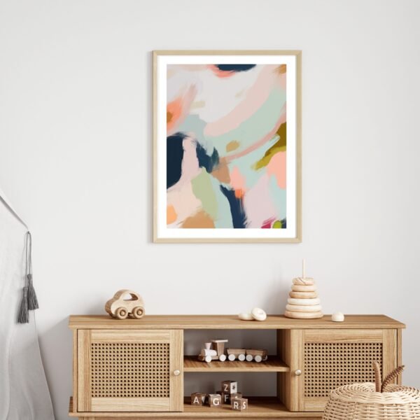 Framed abstract artwork featuring soft colors and fluid shapes displayed on a wall.