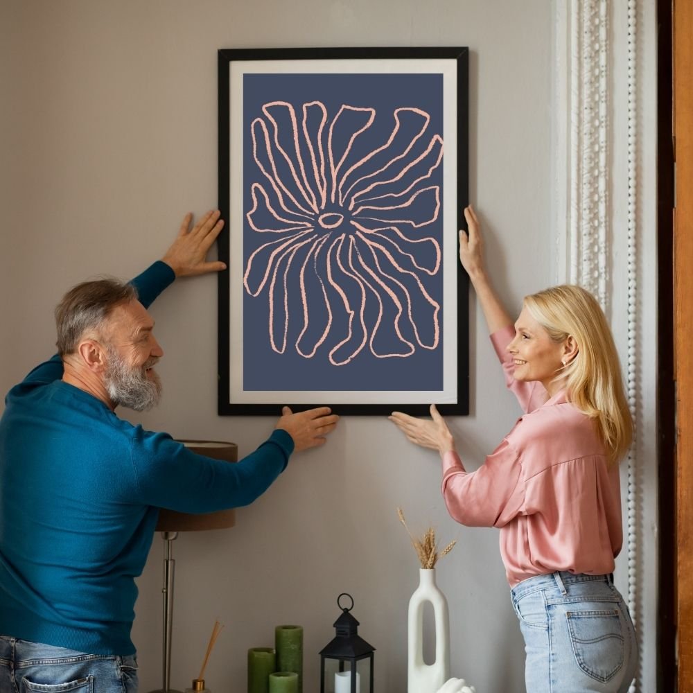 Two individuals placing a framed abstract artwork featuring a floral design on a wall.