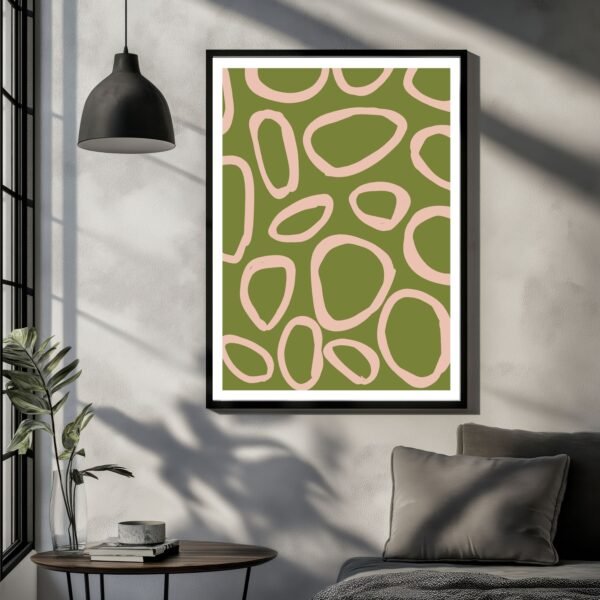 Abstract artwork featuring organic shapes in green and pink tones framed on a wall.